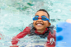child smiling while learning to swim