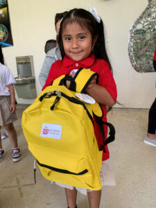 little girl holding yellow backpack